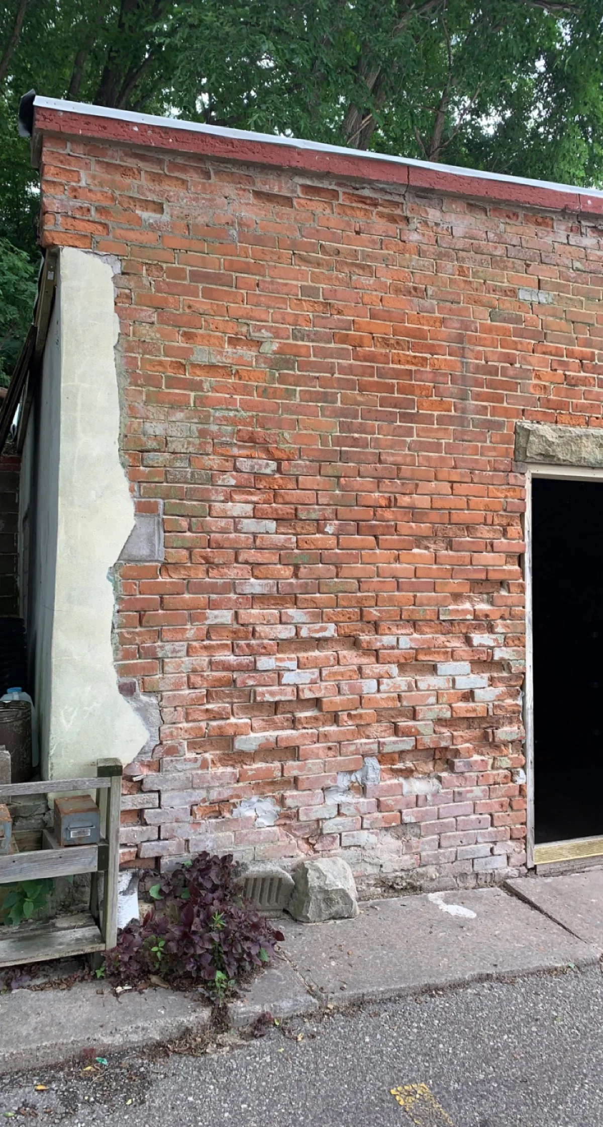 Deteriorated brick wall with spalled faces and failed mortar before restoration