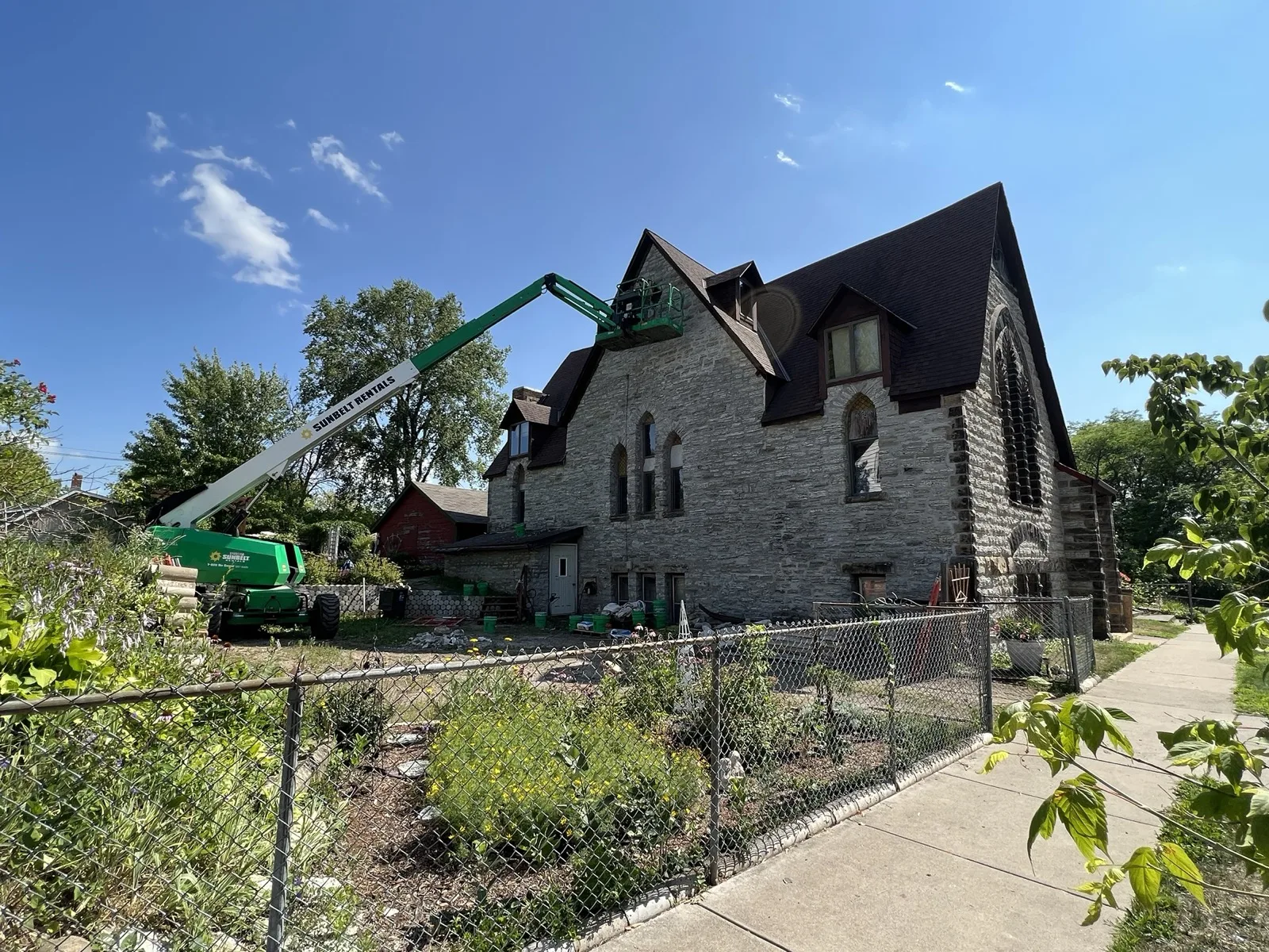 Stone church under masonry restoration with a boom lift reaching the roofline